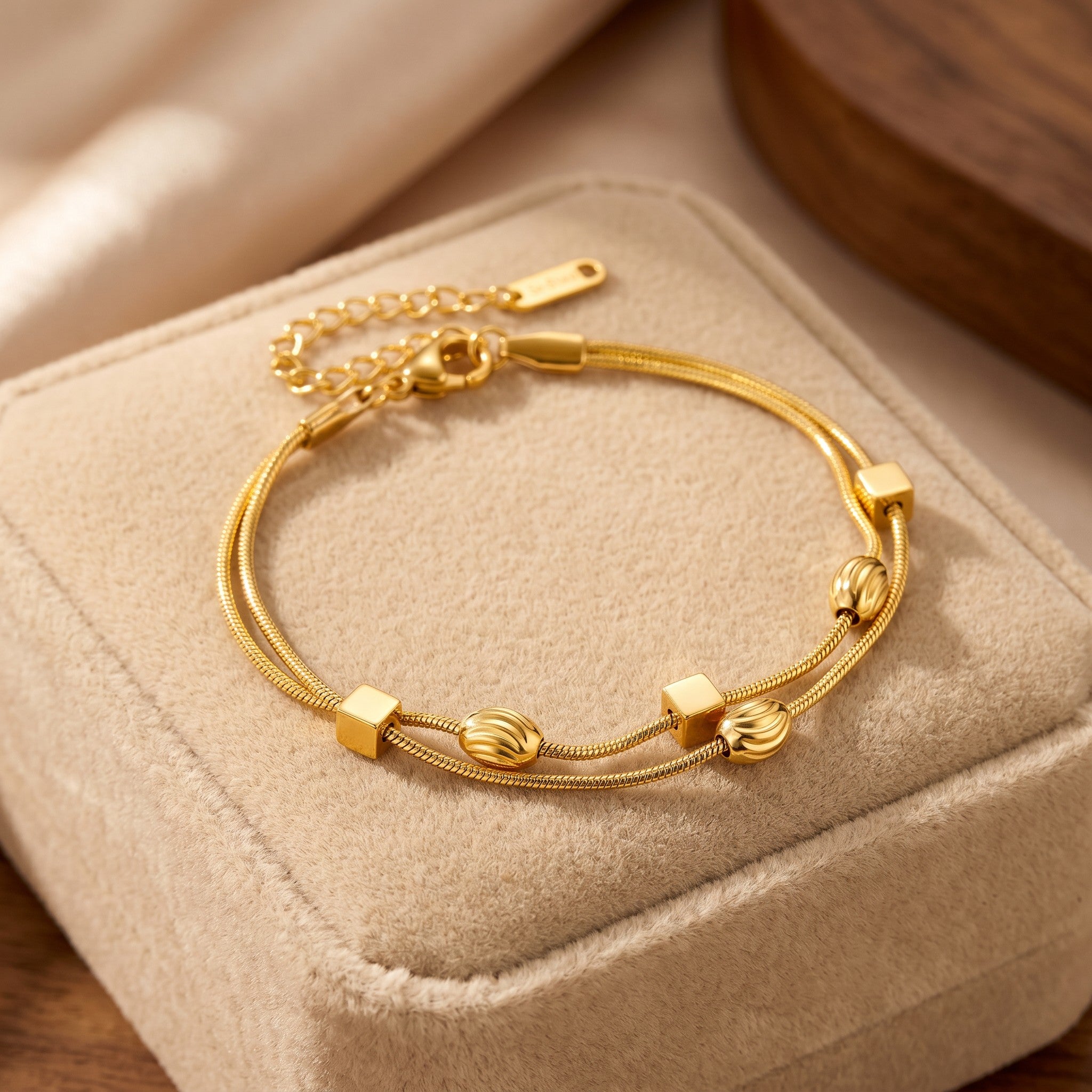 Złota Kraków double chain bracelet with gold-plated surgical steel, featuring cube and ribbed bead charms. Adjustable length.