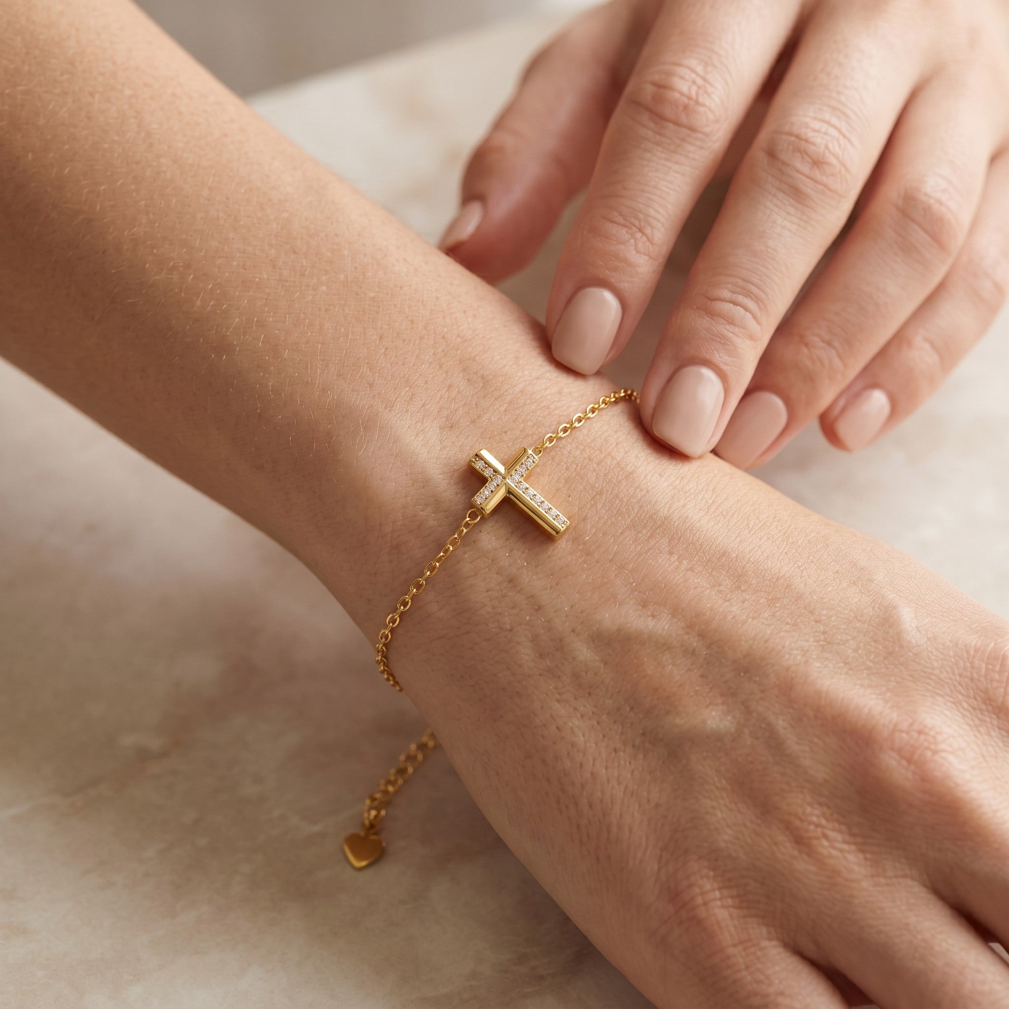 Złota Kraków gold-plated surgical steel bracelet with a cross charm adorned with cubic zirconia. Adjustable length with heart detail.