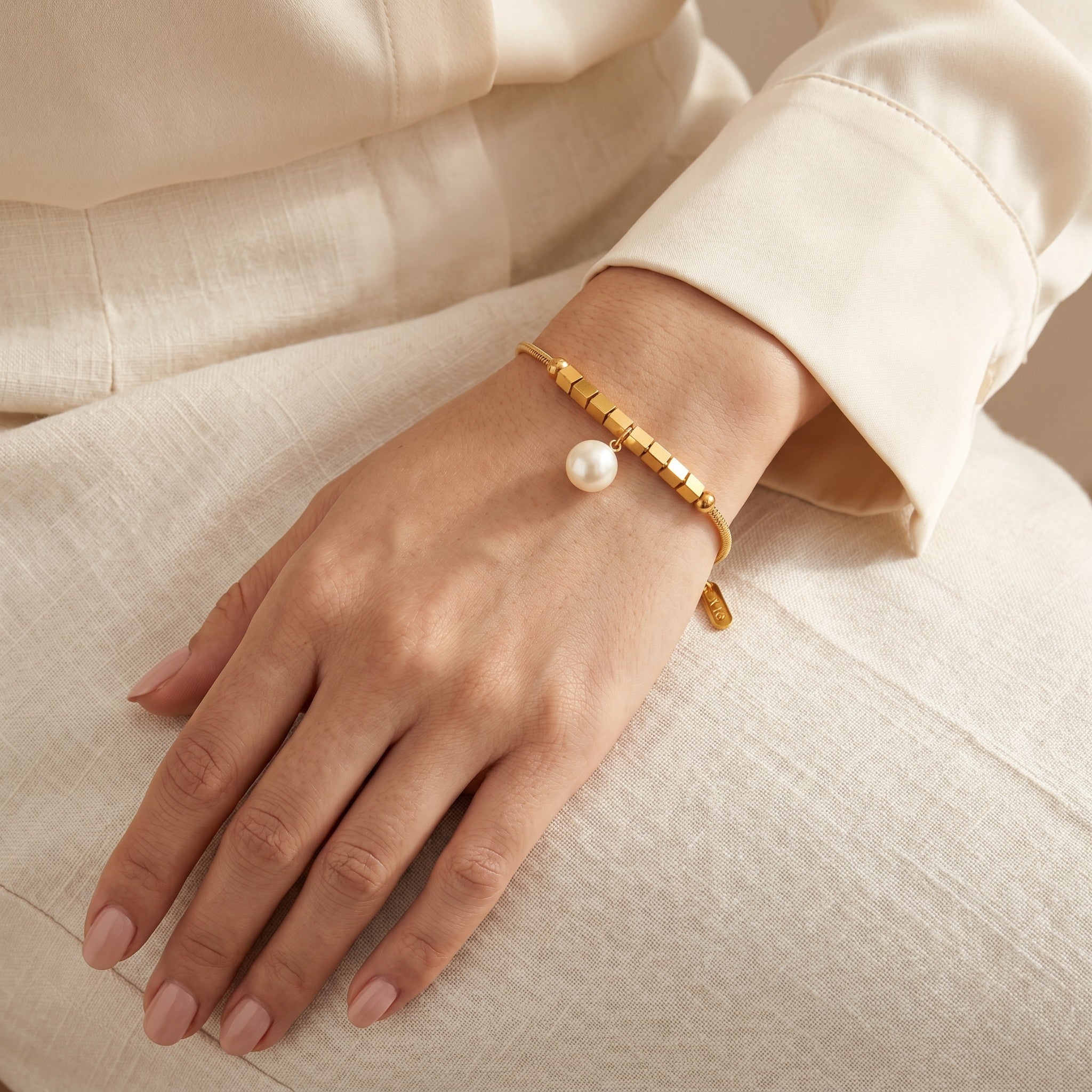 Złota Kraków gold-plated surgical steel bracelet with a synthetic pearl charm and cube accents. Adjustable length.